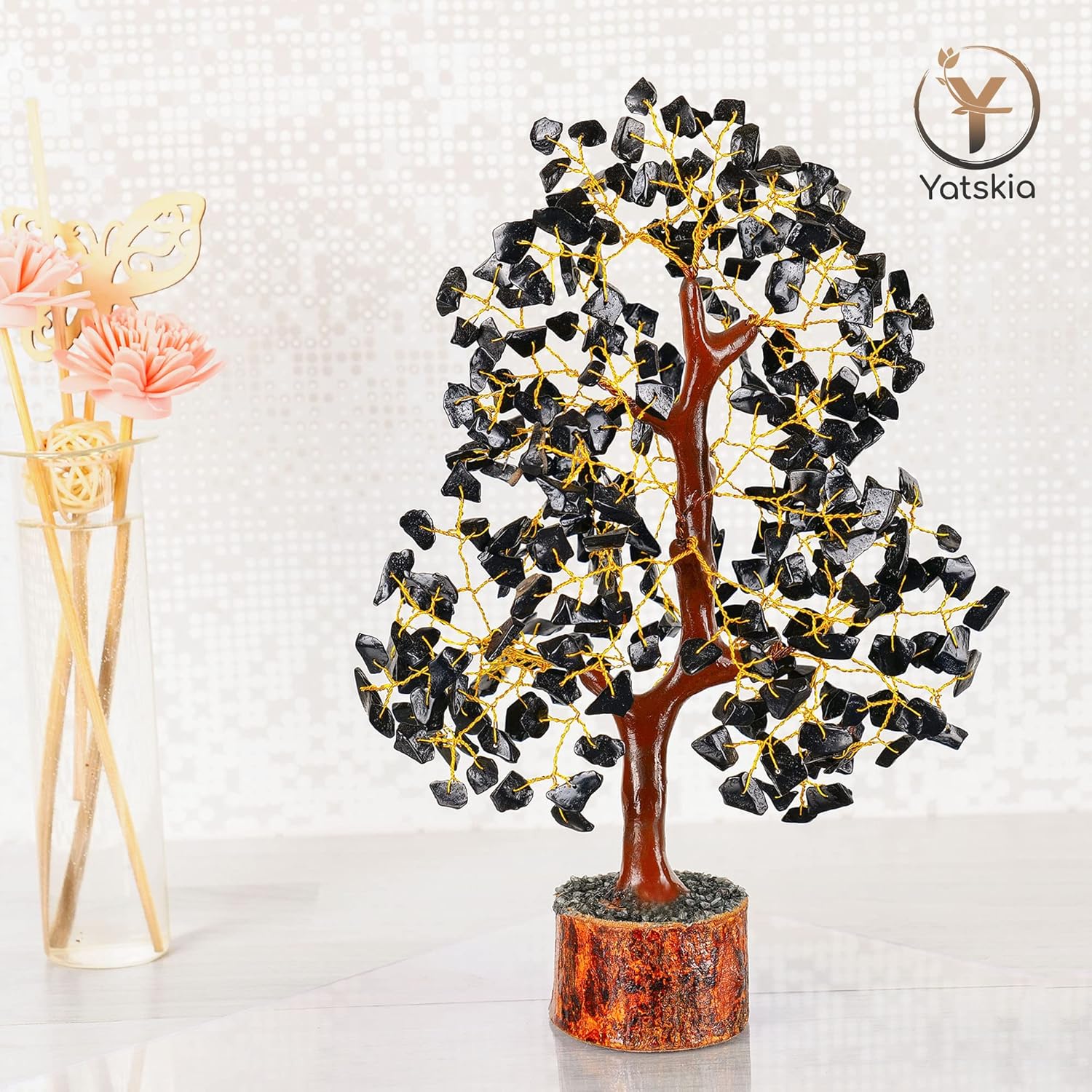 Decorative tree sculpture with black stones and gold accents on a white background