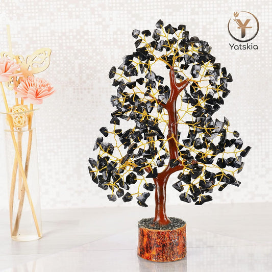 Decorative tree sculpture with black stones and gold accents on a white background